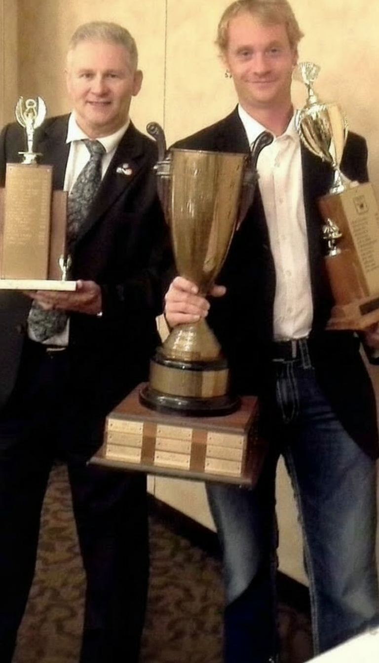 Kristian Charles holding championship trophies with another performer