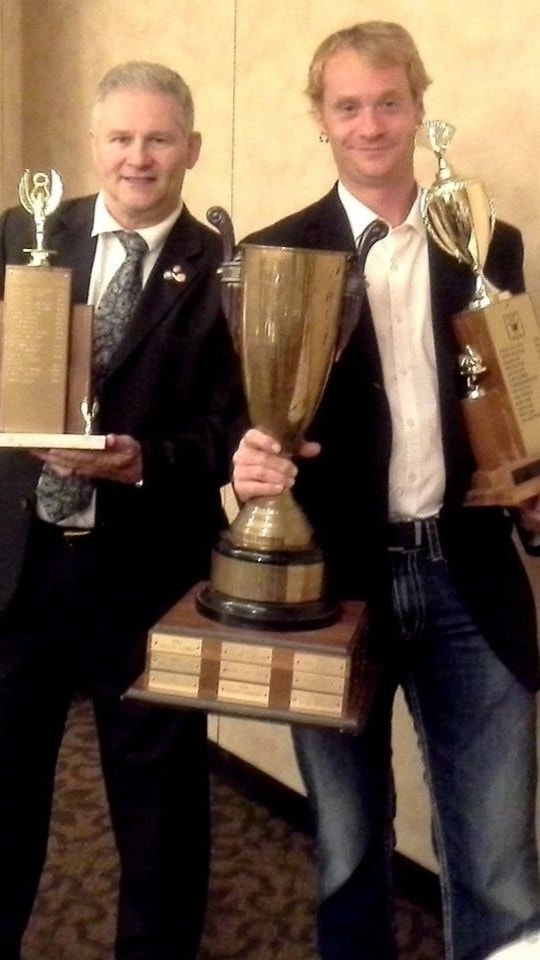 Kristian Charles holding multiple award trophies